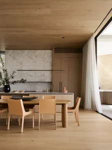 A photograph of a modern residential dining space featuring wood and marble elements.