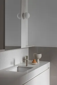 Minimalist bathroom featuring a concrete counter, sink, and brushed metal faucet, with a wooden knob soap dish and a concrete