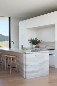 A modern kitchen with minimalist design featuring a marble island and counter.
