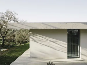 Modern residential exterior with concrete walls and a flat roof in a rural setting.