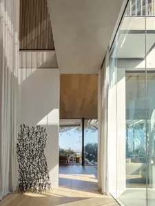 Modern residential interior space with wooden floors, glass walls, and steel elements.