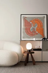 A modern interior design living room featuring a sleek white armchair, a table lamp, and an abstract art painting on the wall