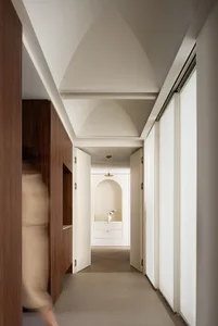 Modern interior design featuring a corridor with wooden paneling and concrete flooring.