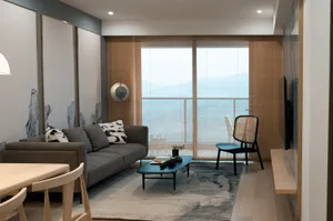 Modern living room with minimalist decor, neutral colors, and a view of the ocean.
