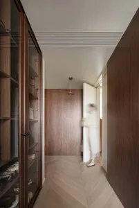 A modern interior wooden walk-in closet with a glass-front cabinet and a wooden floor.