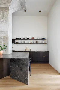 Modern kitchen with marble countertops and black cabinets.