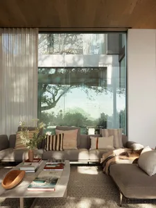 A modern living room with fabric curtains, a glass window, and comfortable seating.