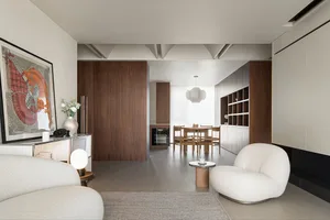 A modern living room with wooden furniture and a marble floor, featuring a round coffee table and a white sofa.