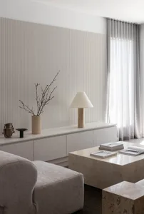 A modern minimalist living room with concrete furniture and a minimalist table lamp, featuring white curtains and a striped w