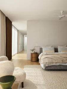 A modern minimalist bedroom with neutral-toned fabrics and furniture.