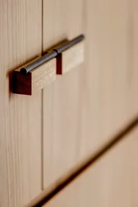 Close-up of a modern cabinet handle made of oak wood with a sleek, minimalist design.