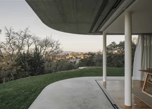 A modern residential outdoor area featuring a concrete patio, wooden deck, and greenery.