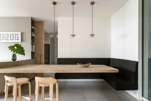 Modern dining area with wooden table, metal stools, and fabric seating.