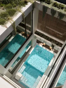 Modern residential pool area enclosed by concrete walls with glass panels.