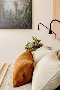 A modern bedroom with neutral-colored bedding and simple, elegant decor.