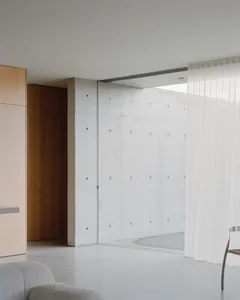 A minimalist interior featuring exposed concrete walls.