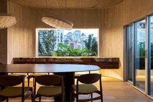 Modern dining room with panelized wood walls, marble accents, and a circular dining table.