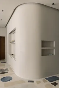 極簡室內空間，混凝土牆面與地板，搭配內嵌式置物架與弧形牆面。
