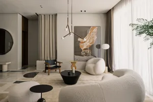 A modern living room with neutral tones, featuring a white sofa, round coffee table, and abstract artwork.