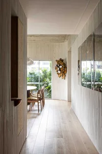 A modern restaurant corridor featuring wooden walls and floor, glass walls, and a wooden hanging decoration.