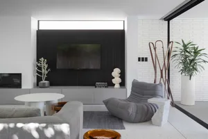 Modern minimalist living room with concrete and marble finishes, featuring a couch, chair, and potted plant.