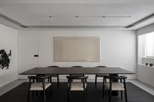 Modern dining room featuring wooden table and black chairs with leather cushions.