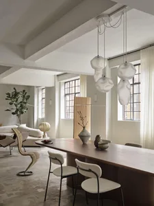Modern living and dining room featuring wood furniture, glass pendant lights, and concrete flooring.
