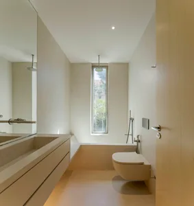A modern minimalist bathroom with a concrete floor, walls, and sink, featuring a large vertical window.