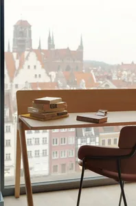 A modern study space featuring a wooden desk, a chair, and books against the backdrop of a cityscape.