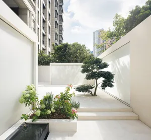 A modern, minimalist garden featuring concrete planters and a sleek, white wall.