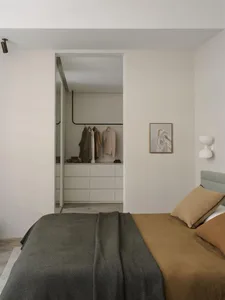 Minimalist bedroom with a neutral blanket and a closet in the background.