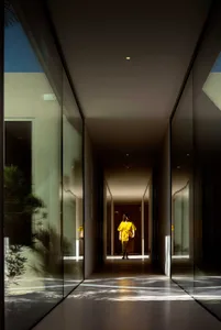 A minimalist corridor with glass walls reflects sunlight, creating a serene ambiance.