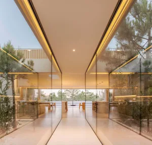 A minimalist interior with glass walls and concrete flooring.