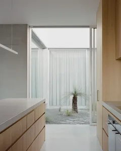 Modern minimalist kitchen featuring wooden cabinets and glass walls