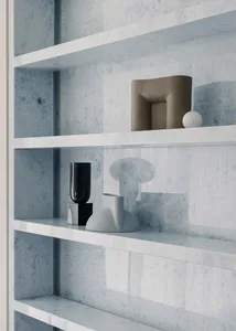 Minimalist marble shelving displaying modern abstract sculptures and vases.