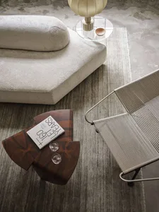 A modern living room featuring a concrete floor lamp and a wooden side table with a book and glasses on it.