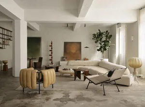 A modern living room with minimalist furniture, a curved sofa, and neutral-toned decor.