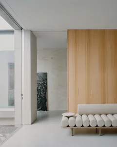 A modern living room with a wooden wall, minimalist furniture, and natural light.