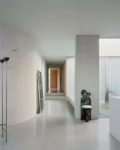 A minimalist residential interior with a concrete floor, white walls, and a simple, modern seating area.