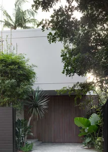 Modern private residence exterior featuring a wooden Sliding Gate with lush greenery surrounding it.