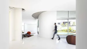 A contemporary living room with white marble floor and curved walls.