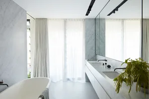 Modern bathroom with white marble walls and floor, a freestanding bathtub, and double sink vanity.