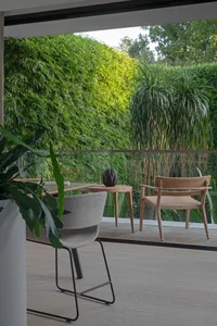 Modern interior patio area featuring wooden furniture and textile accents with lush greenery outside.