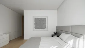 A minimalist bedroom with concrete walls and a bed.
