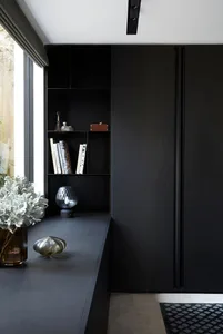 A modern black interior with metallic accents and a glass vase on a shelf.