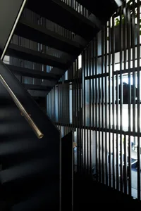 A modern black staircase with metal railings and a glass wall.