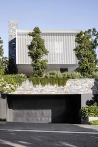 A modern house with stone, cement, and greenery exteriors.