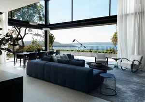 Modern living room featuring a glass couch and black furniture with large windows overlooking a scenic water view.