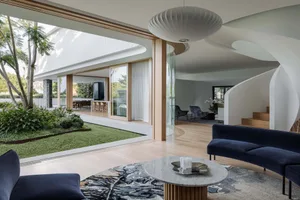A modern living room featuring marble surfaces and wooden elements, glass walls, and a circular pendant light.