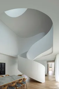 A modern minimalist interior designed with white stone, featuring a spiral staircase.